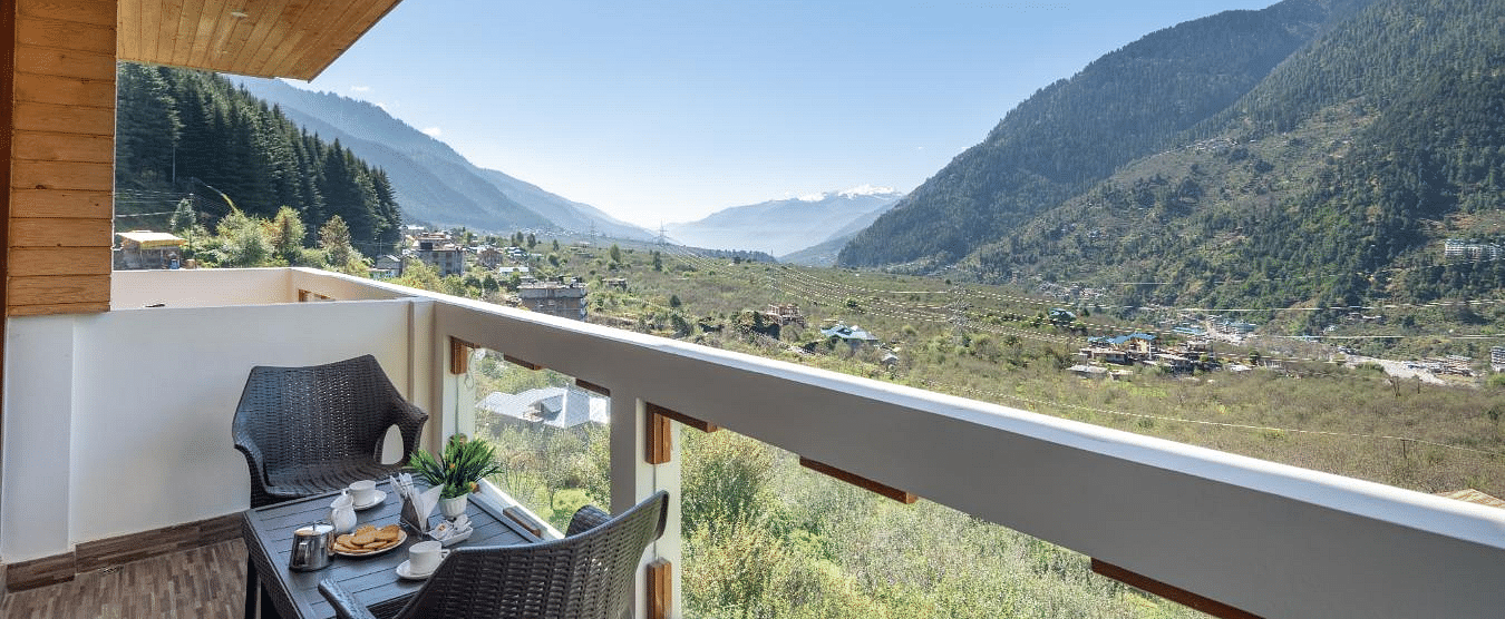 Image of a balcony with a table and chairs overlooking a scenic mountain valley  | DLS Serenity Resort and Spa